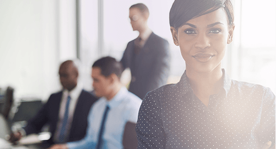 women standing front right with colleagues behind her working 