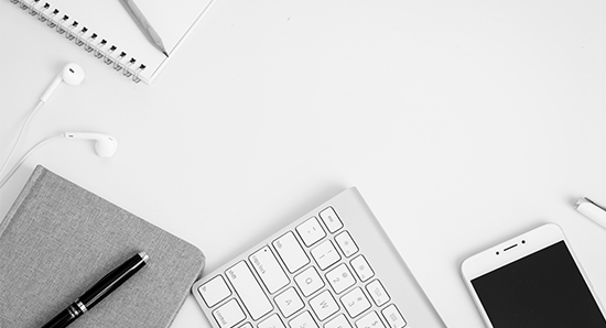 white desk with a keyboard, notebook, pen and mobile 