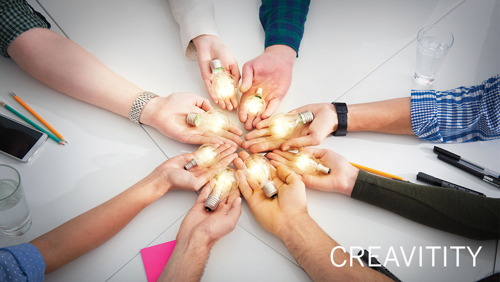 group of people with arms extended in a circle holding lightbulbs